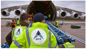 Crew members watch cargo going up into a cargo hold on a plane.