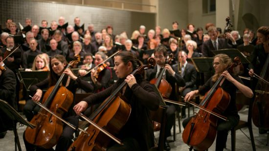 An orchestra playing their instruments in a room.