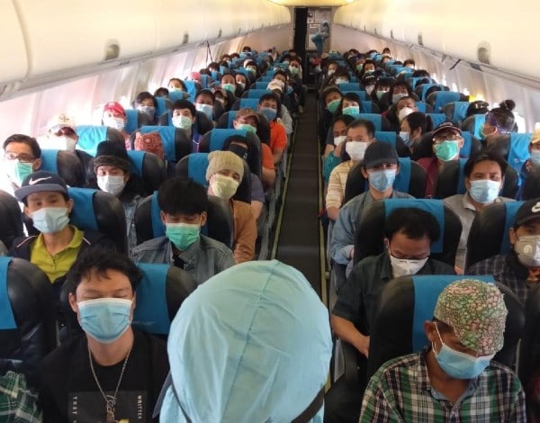 A large group of personnel on a plane, wearing masks.