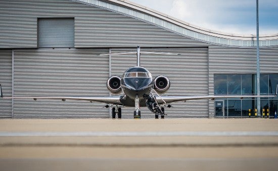 A private jet parked in front of an airport terminal.